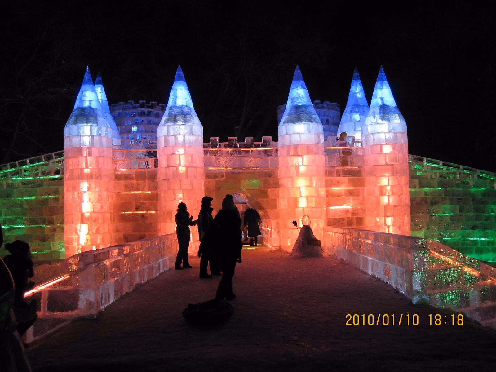 Visitors crossing a bridge through colourful illuminated ice sculptures at Zhaolin Park