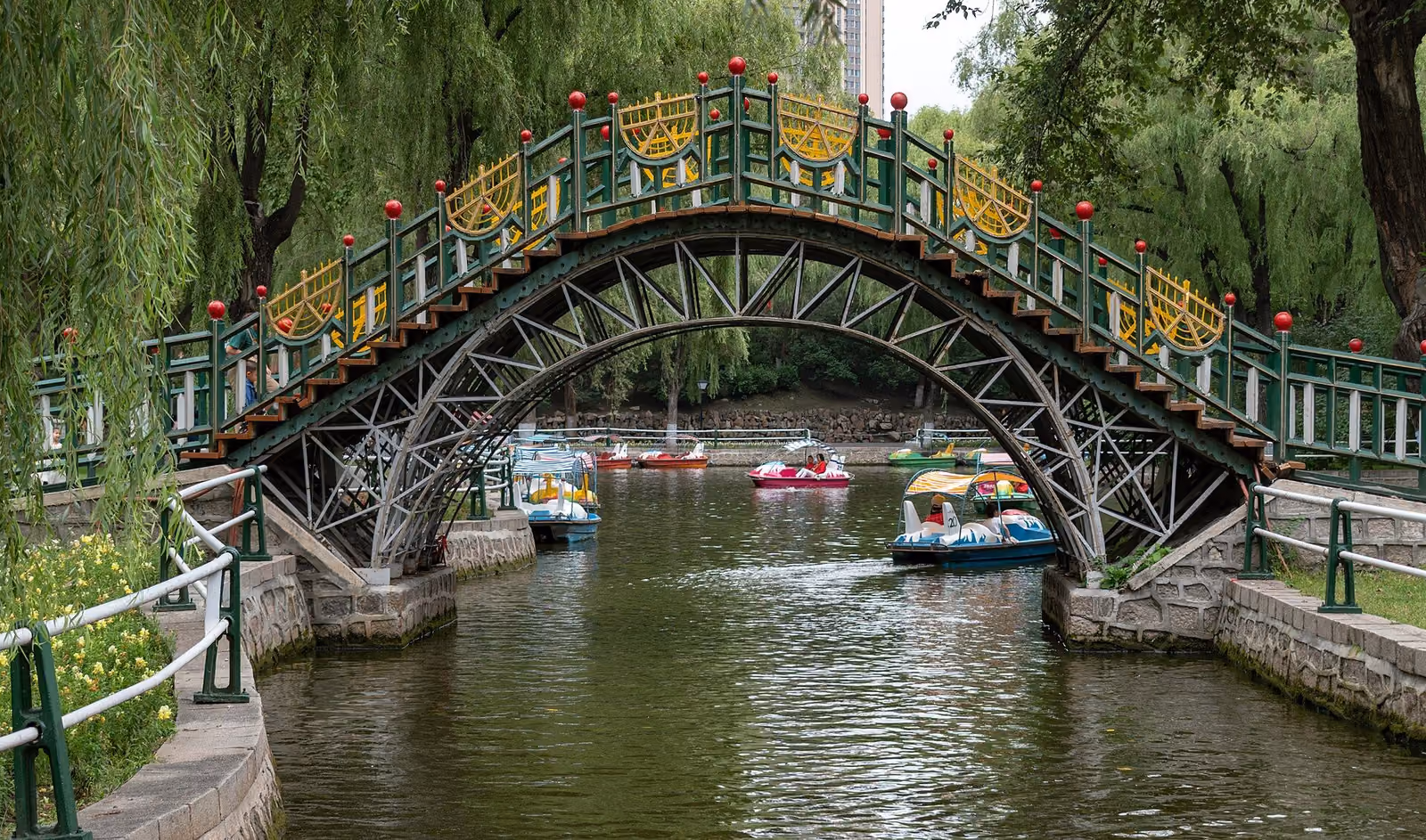Arched bridge, willow trees and pedal boats in Harbin’s Zhaolin Park