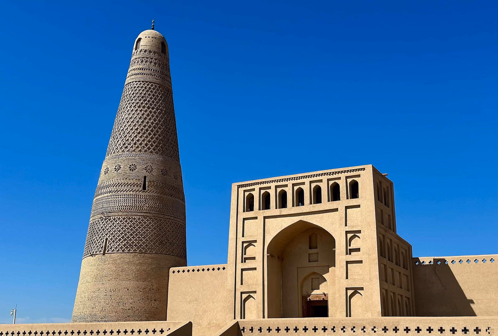 The brickwork of Emin Minaret beside its mosque entrance in Turpan, photographed in 2024